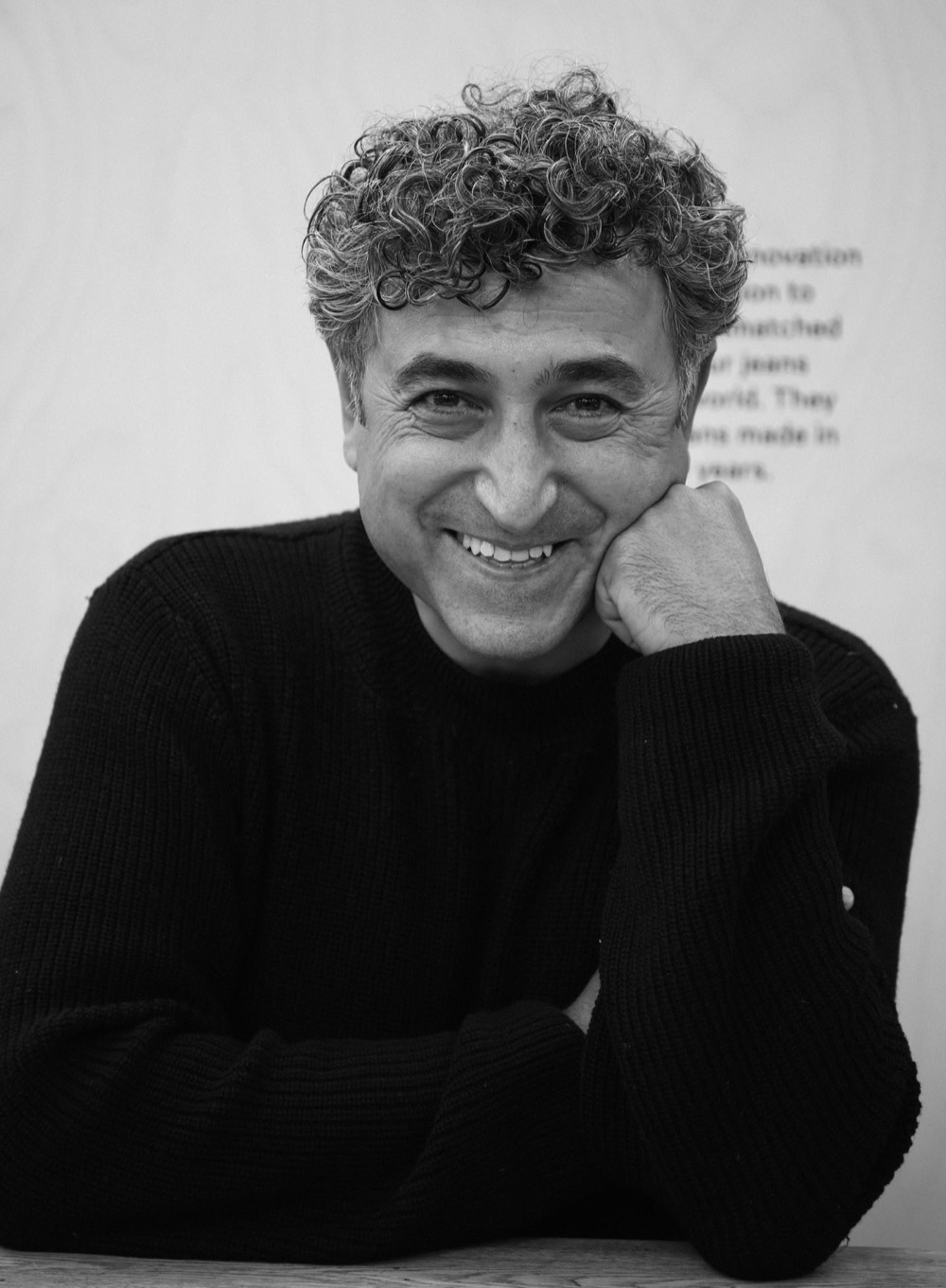 Han Ates, founder of Blackhorse Lane Ateliers, resting his chin on his hand and smiling in front of the factory wall