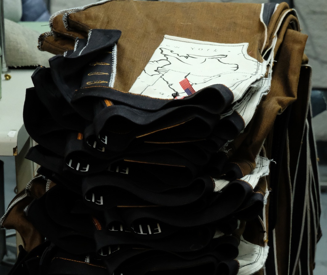 Stacks of cut denim panels and a paper pattern on the workbench in the Fitted Underground workshop