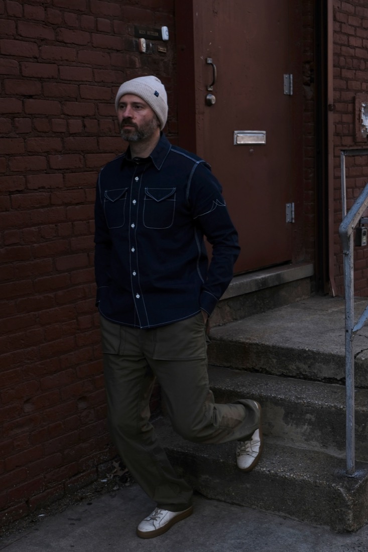 Eric Steffen, founder of Fitted Underground, in a denim work shirt against a Brooklyn brick wall