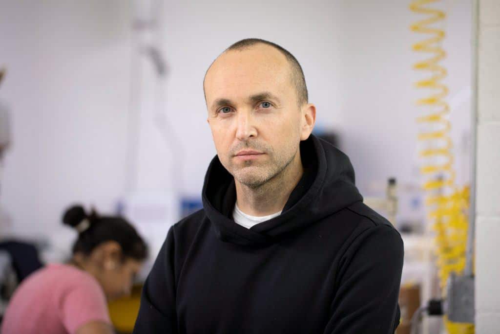 Todd Shelton on the floor of his East Rutherford, New Jersey factory, a seamstress sewing at a machine behind him